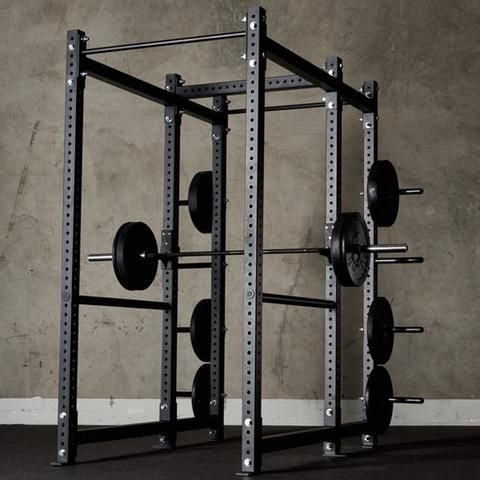 En robust svart power rack med skivstång och viktsvär i ett hemmagym.